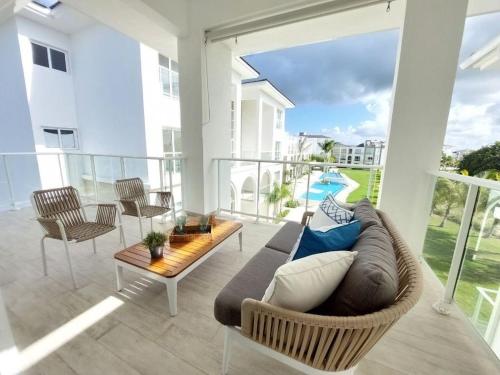a living room with a couch and a table on a balcony at Hard Rock Golf Cozy 1BR • Pool & Golf Views in Punta Cana