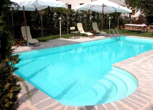 una grande piscina blu con sedie e ombrelloni di Residenza D'epoca Il Biribino a Città di Castello
