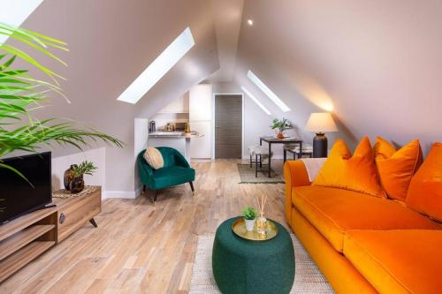 a living room with an orange couch and a green chair at Penthouse Apartment Arundel in Arundel
