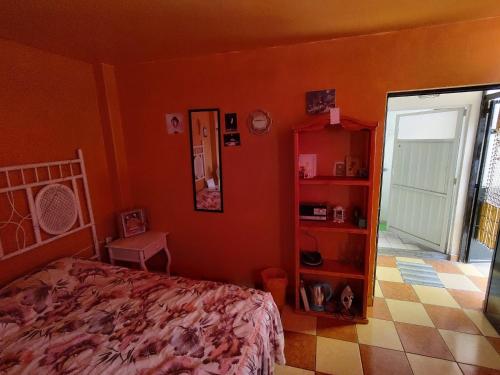 a bedroom with orange walls and a bed and a mirror at Casa El Colibrí CEC in Tehuacán
