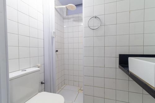 a white tiled bathroom with a toilet and a sink at Apt/Cas Porto de Galinhas in Porto De Galinhas