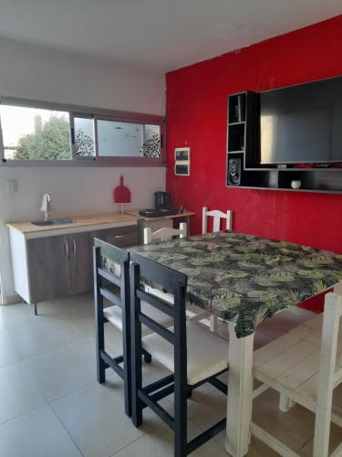 cocina con mesa, sillas y pared roja en La casita de Loy en Tandil