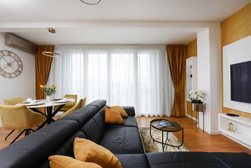 a living room with a black couch and a table at Zadar Sunset Penthouse with spectacular view and jacuzzi in Zadar