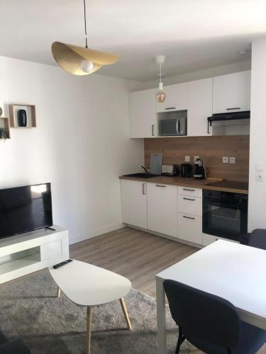 une cuisine avec des placards blancs et une table et des chaises blanches dans l'établissement S&P home, à Tours