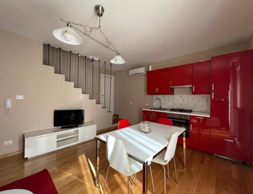 una cocina con armarios rojos y una mesa y sillas blancas. en La Dolce Vita, en Bovino