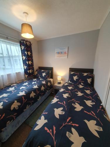 a bedroom with two beds with birds on them at Sands Holiday Chalet in Scratby