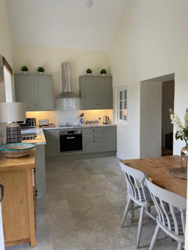 a kitchen with green cabinets and a wooden table at The Cobbles in Towcester
