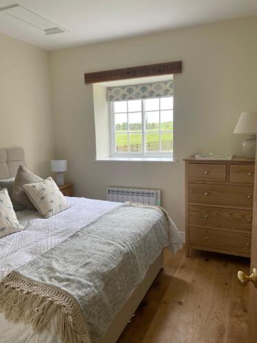 a bedroom with a bed with a window and a dresser at The Cobbles in Towcester