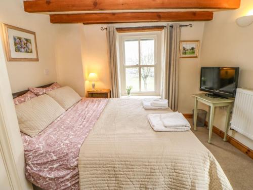 a bedroom with a large bed and a television at Corner Cottage in Staindrop