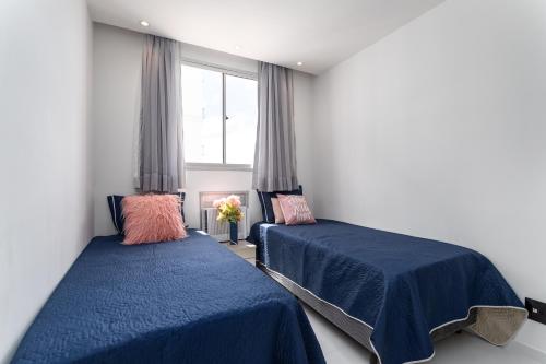 1 dormitorio con 2 camas con sábanas azules y ventana en Apartamento 2 quartos a 4 minutos do Rio centro e jeunesse arena na barra da Tijuca, en Río de Janeiro