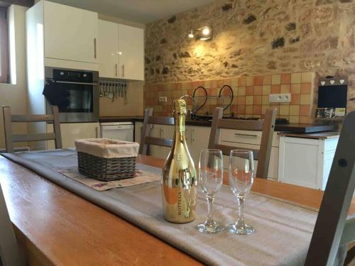 a bottle of champagne and two wine glasses on a table at Peaceful, comfortable retreat with pool in Montcléra