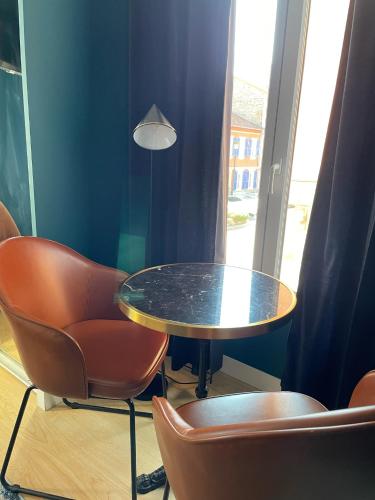 a table and chairs in a room with a window at Ostan Hôtel Boutique in Roquebillière