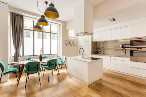 une cuisine avec des placards blancs et une table avec des chaises vertes dans l'établissement Design et confort near Champs Elysees, à Paris