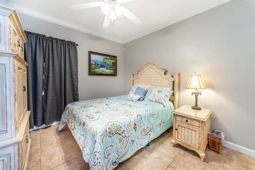 een slaapkamer met een bed en een tafel met een lamp bij Boardwalk 1406 in Panama City Beach