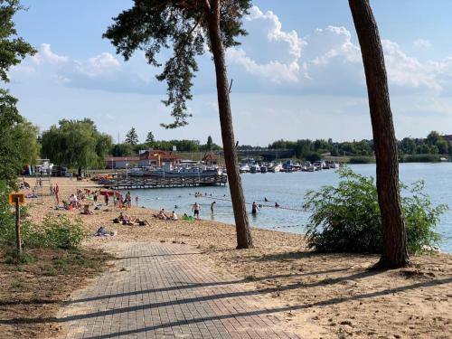 a beach with people in the water and a pier at Balans nad Jeziorem in Ślesin