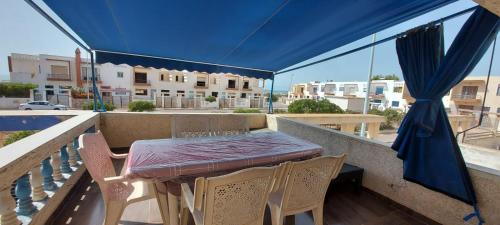 einen Tisch und Stühle auf einem Balkon mit blauem Baldachin in der Unterkunft villa swiriya atlantique in Souira Guedima