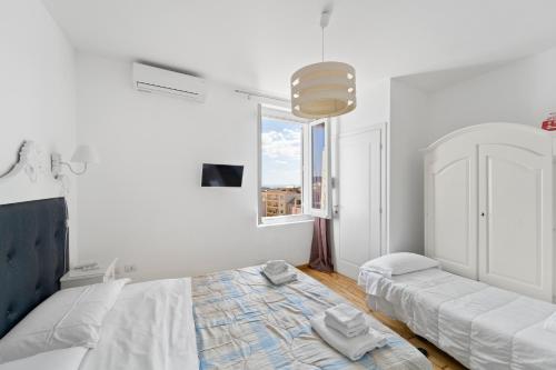 a white bedroom with a bed and a window at Domus Karalis in Cagliari