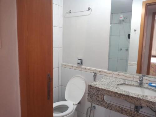 a bathroom with a toilet and a sink and a mirror at APARTAMENTO AGUAS DA SERRA 713 A in Rio Quente