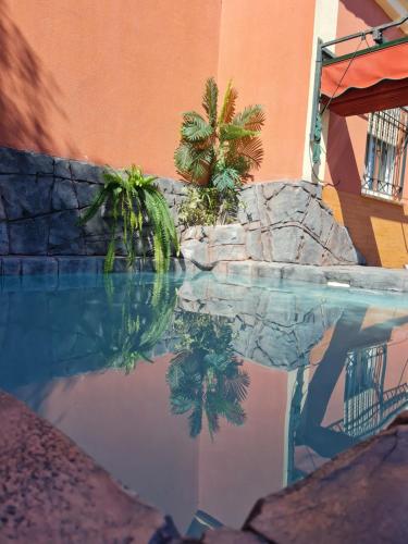 uma piscina de água com palmeiras e um edifício em Casa Camino del Agua em Castilleja de la Cuesta