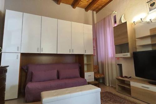 sala de estar con sofá púrpura y armarios blancos en a casa di Max, en Trezzo sullʼAdda