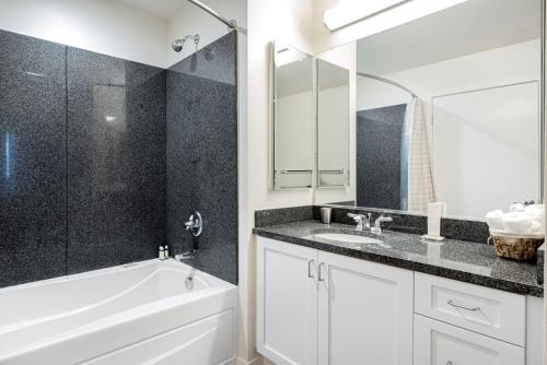 ein Badezimmer mit einer weißen Badewanne, einem Waschbecken und einem Spiegel in der Unterkunft Santa Clara 1BR w Parking Gym nr Groceries SFO-437 in Santa Clara