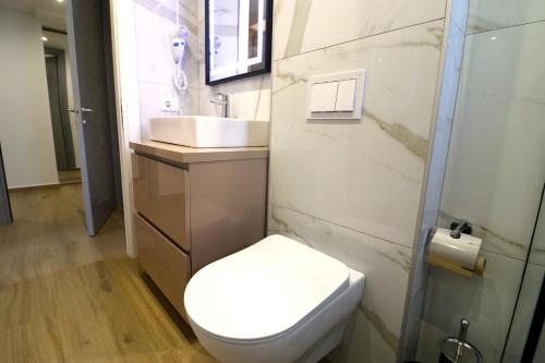 a bathroom with a white toilet and a sink at Fegi Rooms in Himare