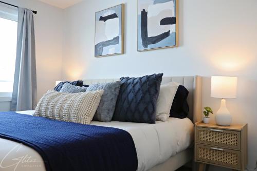 um quarto com uma cama com almofadas azuis e brancas em Modern Retreat 3 King Beds,Garage,Disney em Edmonton