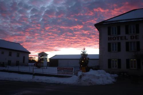 a building with a christmas tree in front of a sunset at La Caquerelle in Col des Rangiers