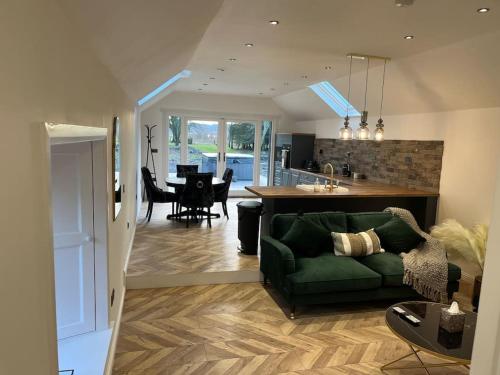 a living room with a green couch and a kitchen at West Loch Farm Bothy in Peebles