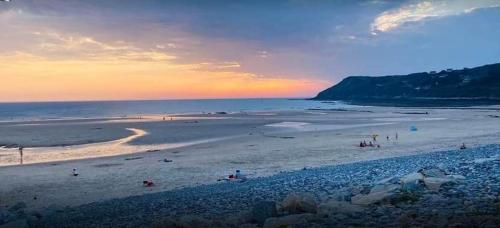 a beach with people on the sand and the ocean at Maison de charme in Benoîtville