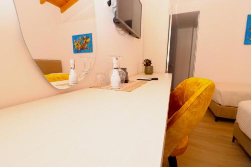a white counter with a mirror and a yellow chair at Fegi Rooms in Himare