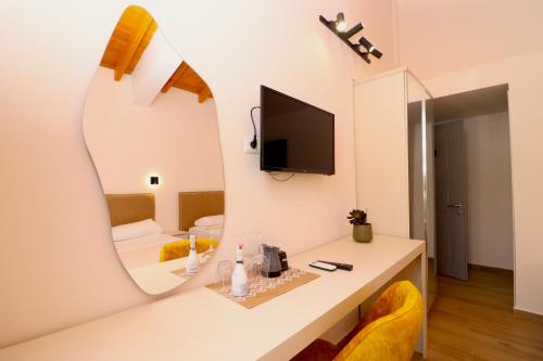 a room with a desk with a mirror and a tv at Fegi Rooms in Himare