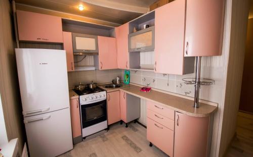 イジェフスクにあるPerina Innのピンクのキャビネットと白い冷蔵庫付きのキッチンが備わります。