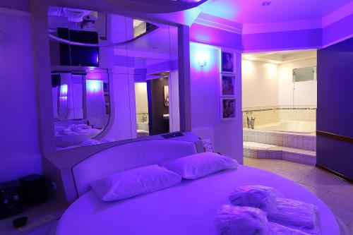 Habitación púrpura con cama y bañera en Liberty Motel, en Saltinho