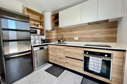 una cocina con electrodomésticos de acero inoxidable y armarios de madera en Mereani flat brand new condo in the center of Papeete en Papeete