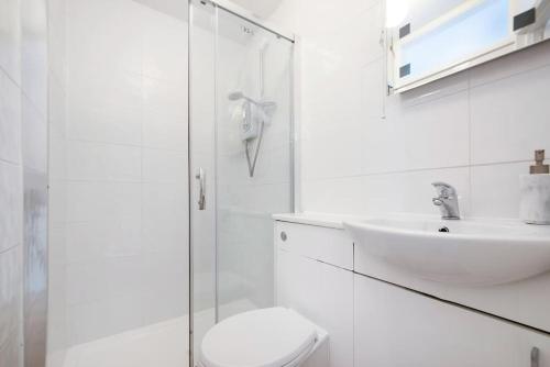 La salle de bains blanche est pourvue de toilettes et d'un lavabo. dans l'établissement flat in south west London 1 min to the station, à Londres