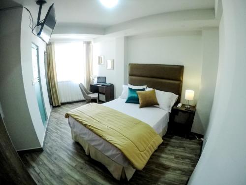 a bedroom with a bed and a desk and a window at Hotel Viaggiatore in Cochabamba