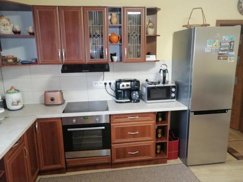 a kitchen with wooden cabinets and a stainless steel refrigerator at Útulný Domček Privat Bedrich in Poprad