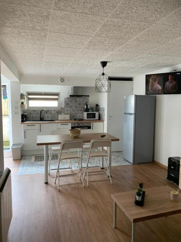 une cuisine avec une table, des chaises et un réfrigérateur dans l'établissement appartement dans maison basque, à Mouguerre
