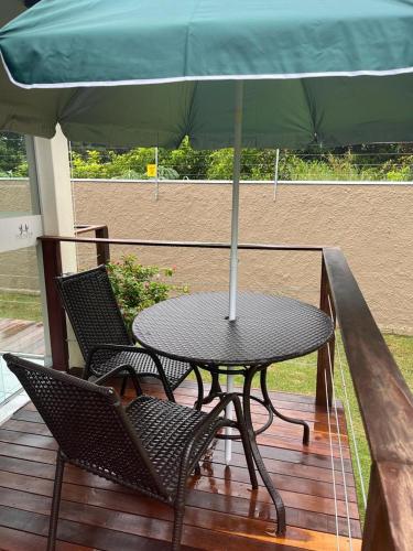 a table and two chairs with an umbrella on a deck at POUSADA ACONCHEGO MT in Chapada dos Guimarães