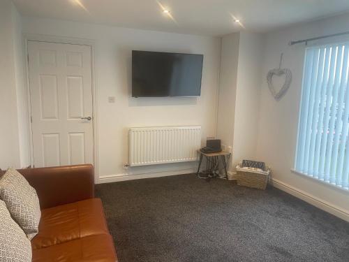 salon z kanapą i telewizorem na ścianie w obiekcie Lovely 3 Bed Bungalow with garage, close to Brecon Beacons & Bike Park Wales w mieście Merthyr Tydfil