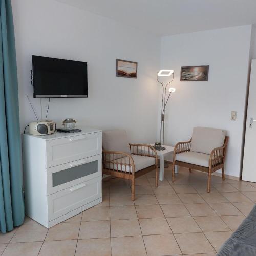 ein Wohnzimmer mit einem TV und 2 Stühlen in der Unterkunft Frische Brise 10.05 in Cuxhaven