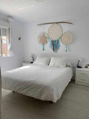 a white bedroom with a bed and hanging decorations at Ático en Barbate in Barbate