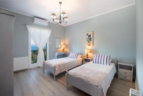 a white bedroom with two beds and a window at Villa Levanda (Loggos Paxos) in Longós