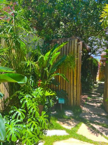 a garden with a wooden fence and some plants at Casa d'Aroeira Residencial Boutique - Centro de Juqueí - 2 quadras do mar - Serviço de Praia - Roupa de Cama 600 fios algodão Egípcio - Toalhas Banho e Praia - Tudo Novo - Estacionamento Interno - Cozinha - Consulte unidades com Ofurô Hidro e Cromoterapia in Juquei