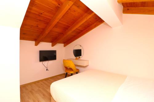 a bedroom with a white bed and a yellow chair at Fegi Rooms in Himare