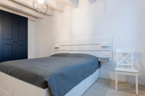 a white bedroom with a bed and a chair at Verona Urban Apartment in Verona