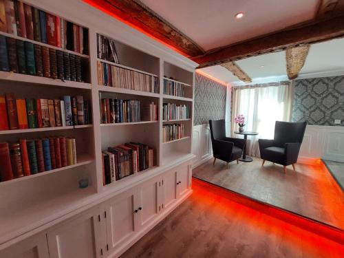 a library with book shelves filled with books and chairs at AnaCapri Gästehaus Verona in Ueckermünde