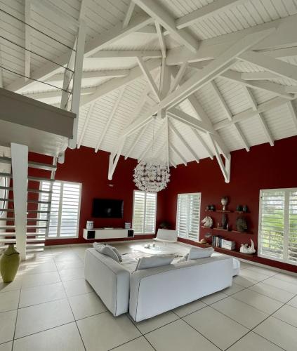 a living room with a white couch and red walls at Villa Estheria in Sainte-Anne
