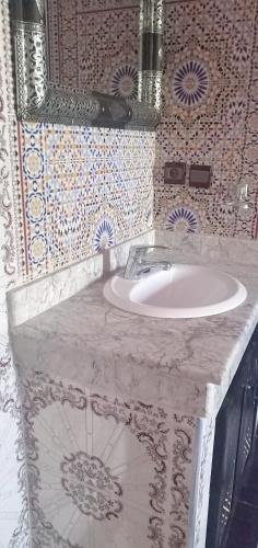 y baño con lavabo blanco y espejo. en Dar LBAHJA 2, en Ouzoud